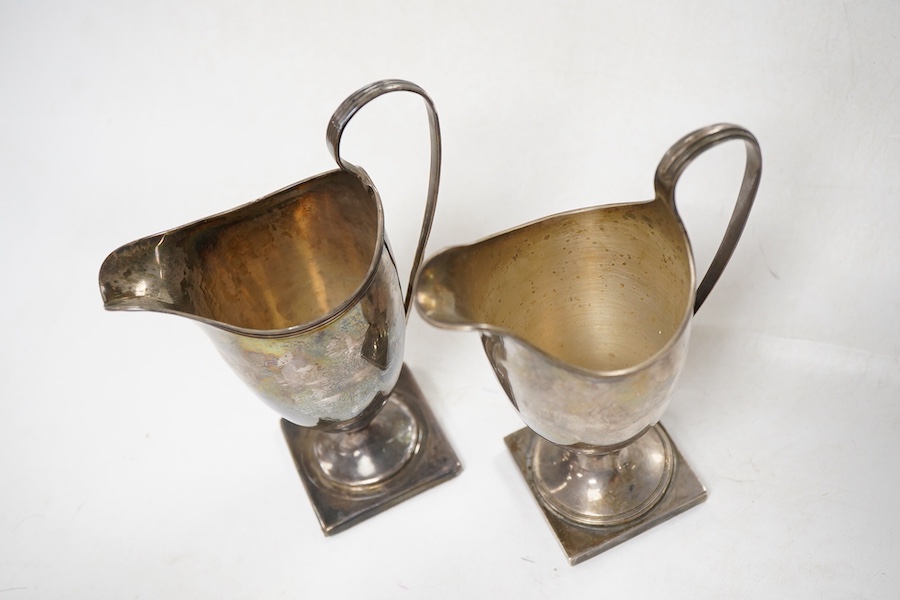 A George III silver helmet shaped cream jug, London, 1795, height 15cm, weighted, together with a later similar cream jug, Birmingham, 1962.